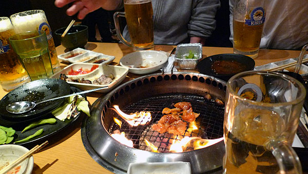 Yakiniku - a table full of beers and food, with beef grilling in process.