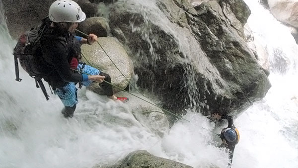 Climbing a waterfall, guide at the top and climber working their way up.