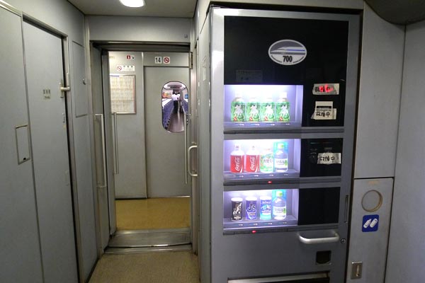 Vestibule area between bullet train cars, with a vending machine and toilets.