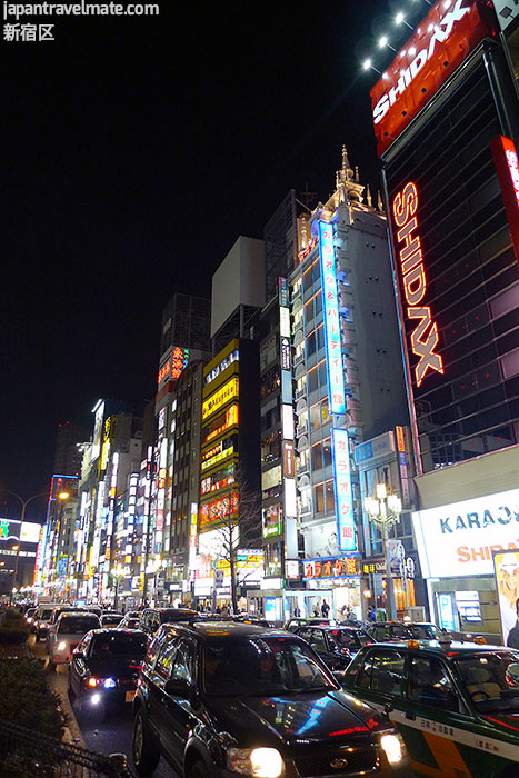 Shinjuku at night, with shops and illuminated trees.